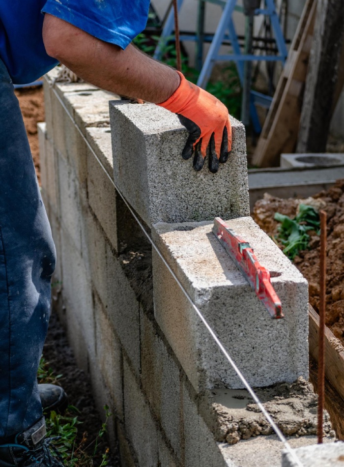 Pose de parpaings sur lit de mortier avec alignement au cordeau et contrôle du niveau